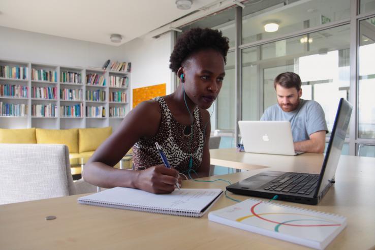 Two people sitting at different desks with computers 